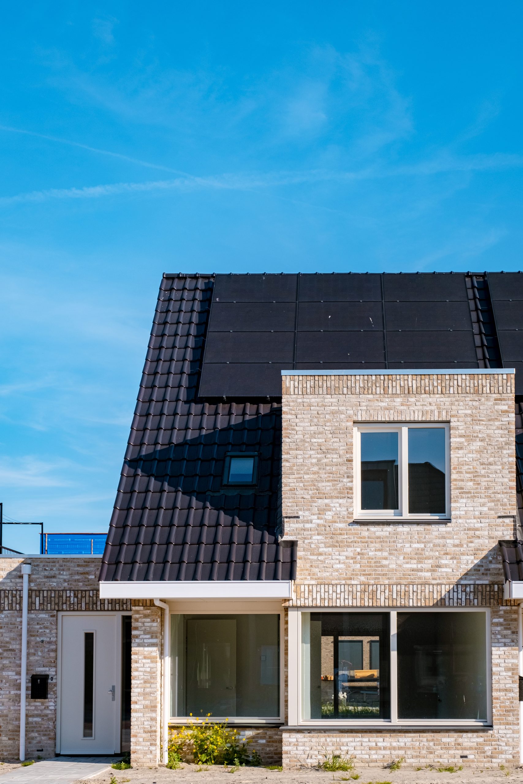 Panneaux solaires installés sur le toit d'une maison avec de nombreuses fenêtres, sous un ciel serein